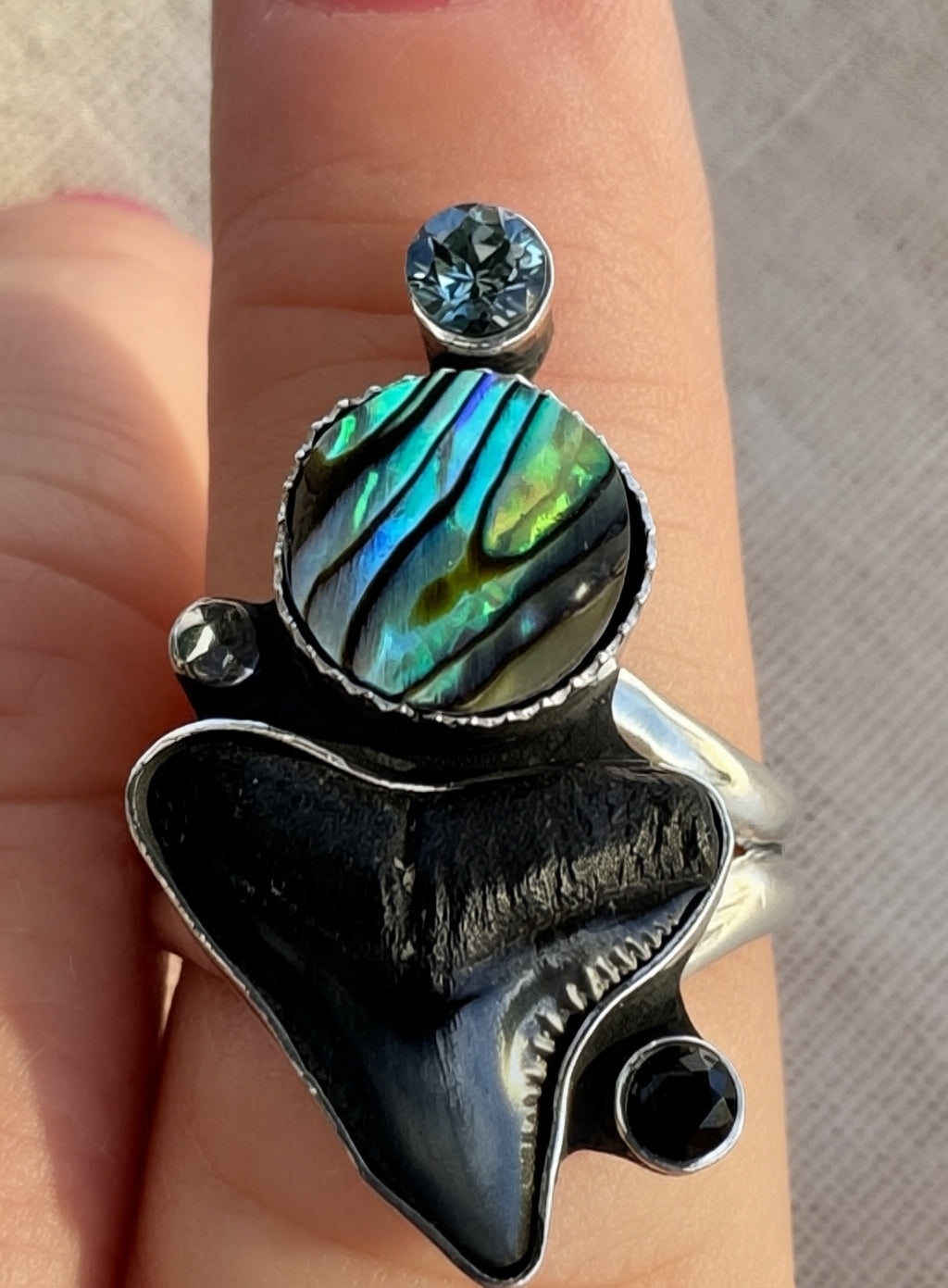 Abalone, shark tooth and spinel statement ring worn on hand showing substantial split shank band and one-of-a-kind handcrafted silverwork by Sun Salt Silver