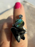 Handcrafted sterling silver statement ring featuring faceted gray and black spinel, iridescent abalone shell, and fossilized shark tooth in vertical totem composition with split shank band