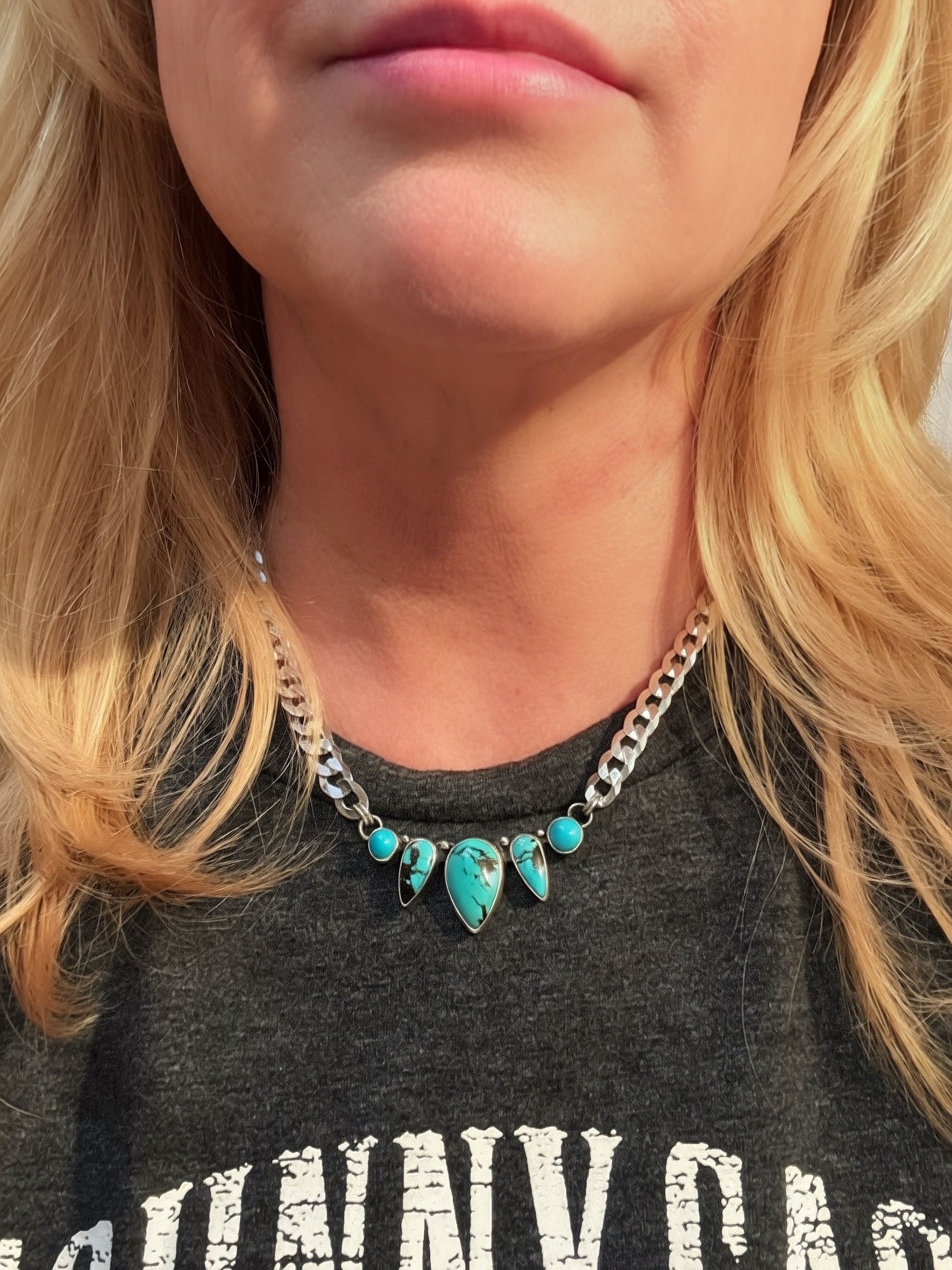 Handcrafted sterling silver curb chain necklace with Blue Dream and Sleeping Beauty turquoise bezel settings, worn at collarbone length