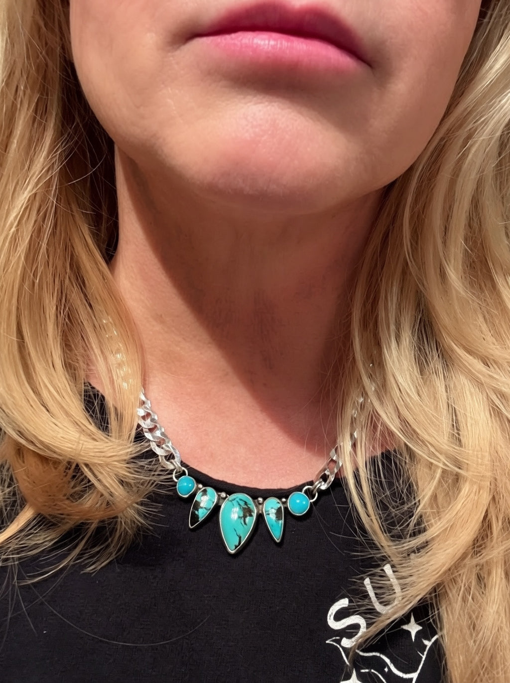 Close-up of a person wearing a turquoise necklace with a blurred background