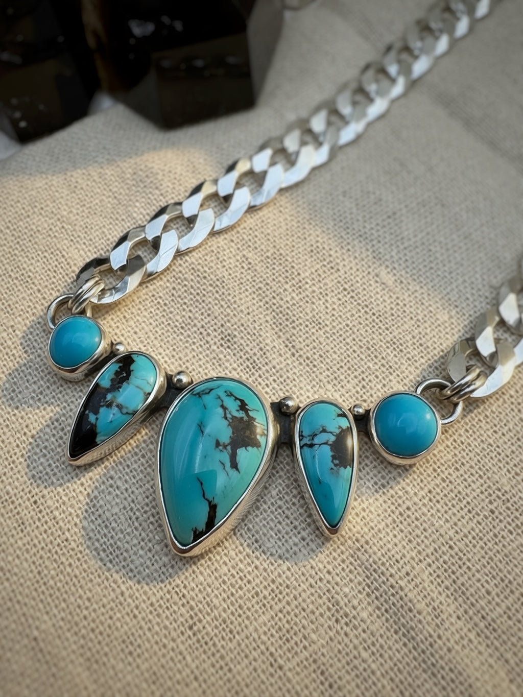 Silver necklace with turquoise stones on a textured fabric background