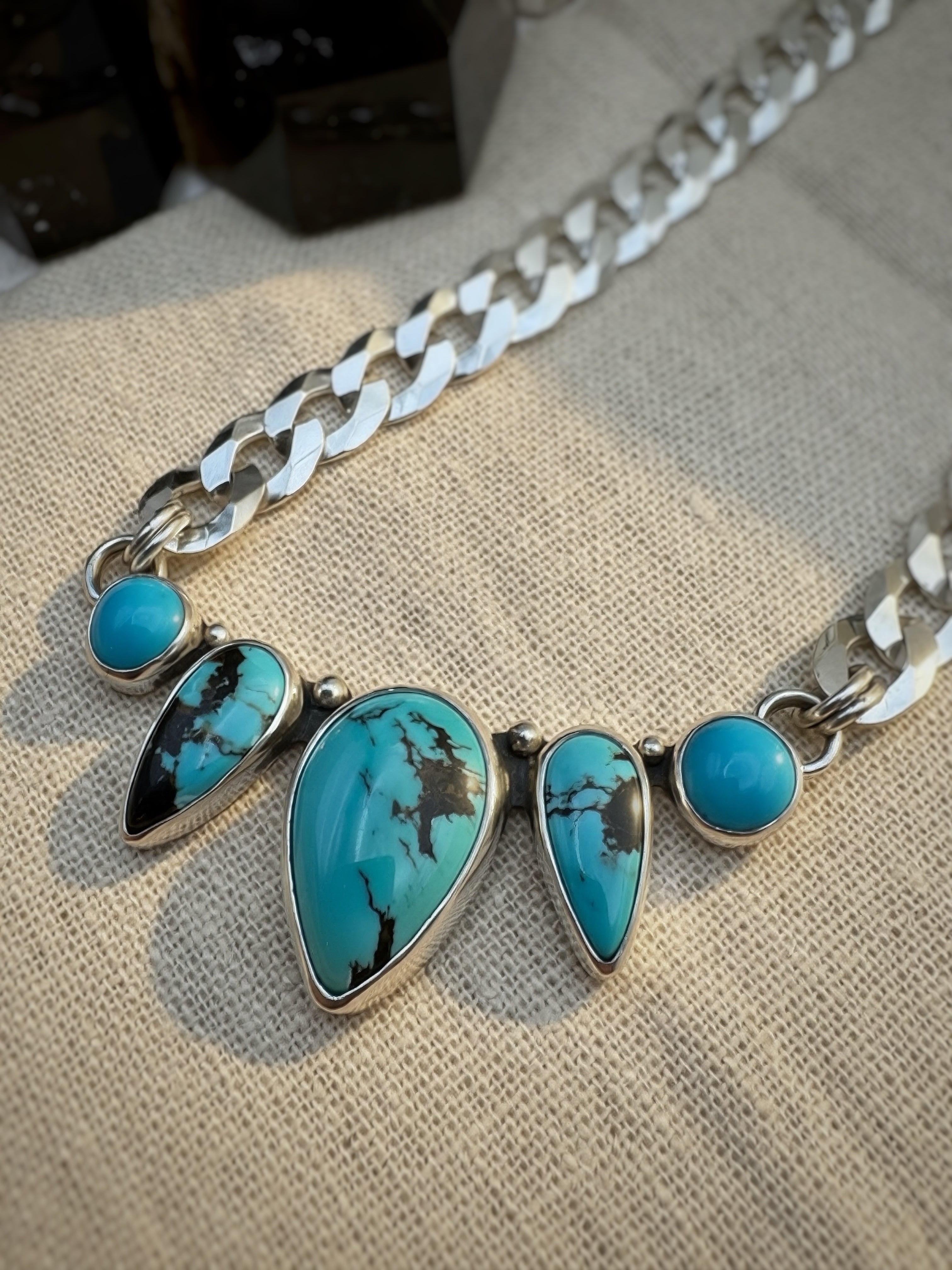 Silver necklace with turquoise stones on a textured fabric background