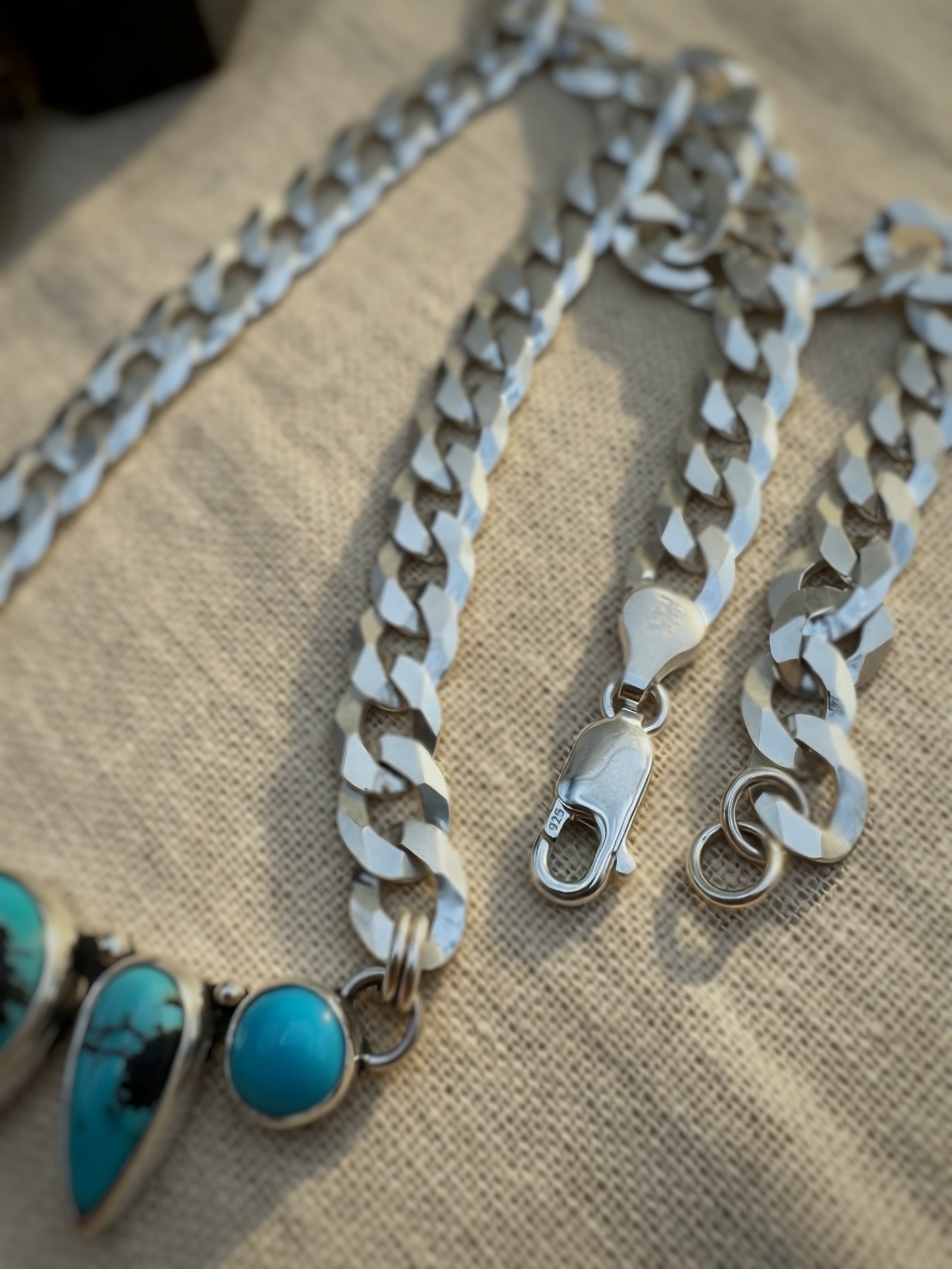 Silver chain necklace with turquoise on a beige fabric background