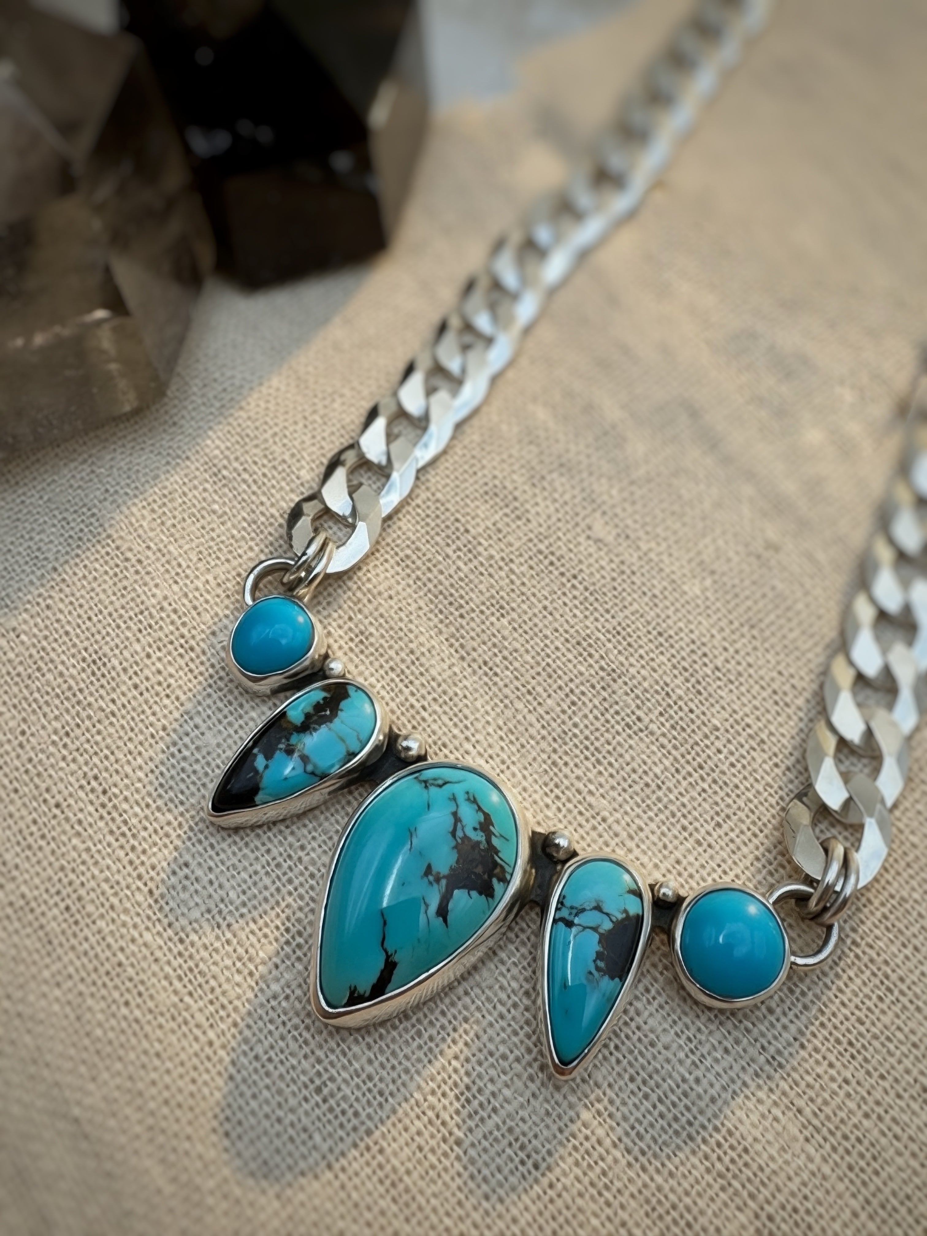 Silver necklace with turquoise stones on a beige fabric background
