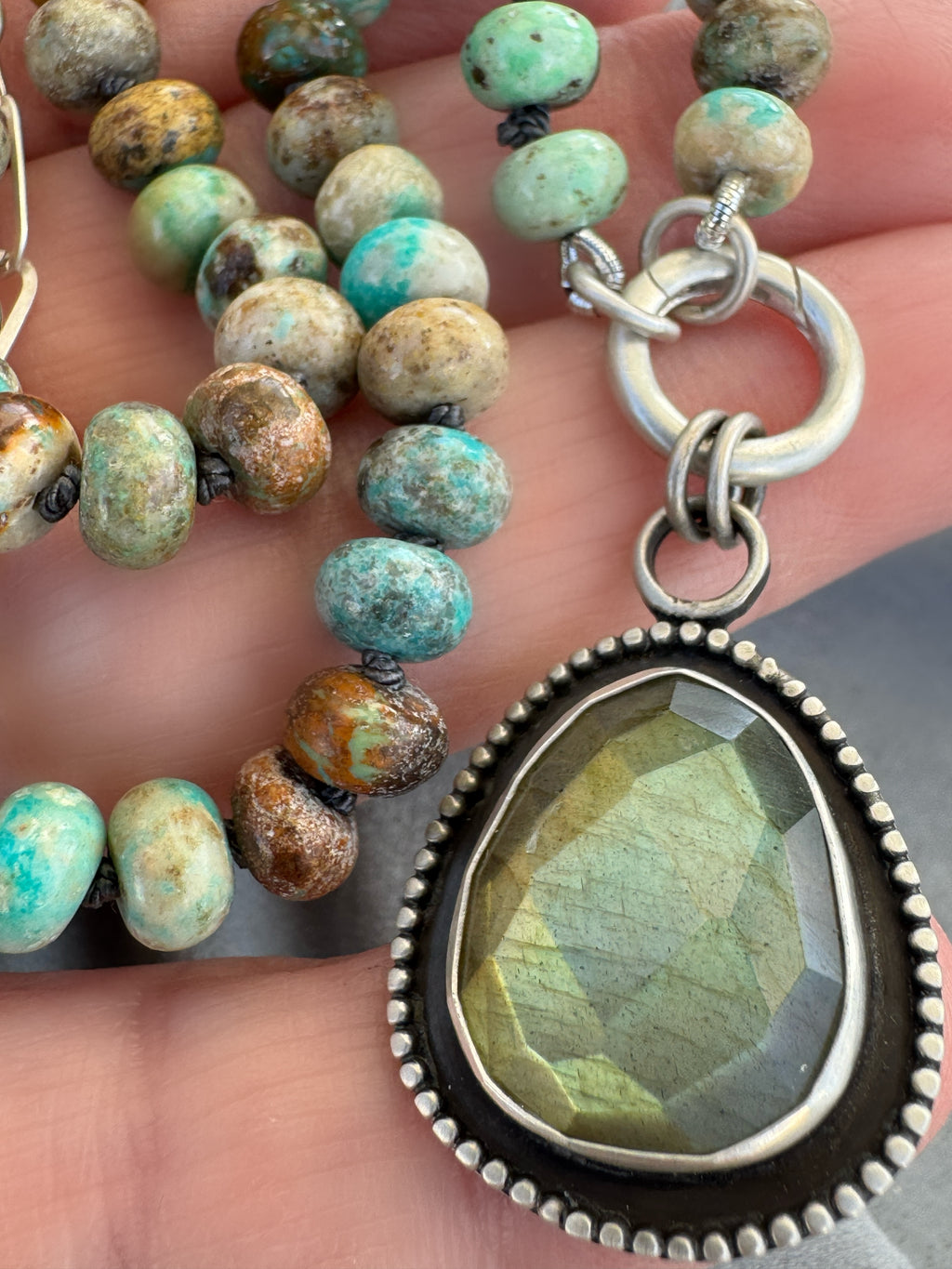 Close-up of the Desert Aurora rose-cut labradorite pendant showing its gold-to-green flash, fine silver bezel and oxidized satin finish.