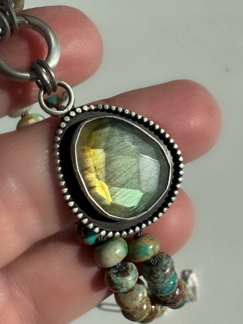 Close-up of the Desert Aurora rose-cut labradorite pendant showing its gold-to-green flash, fine silver bezel and oxidized satin finish.