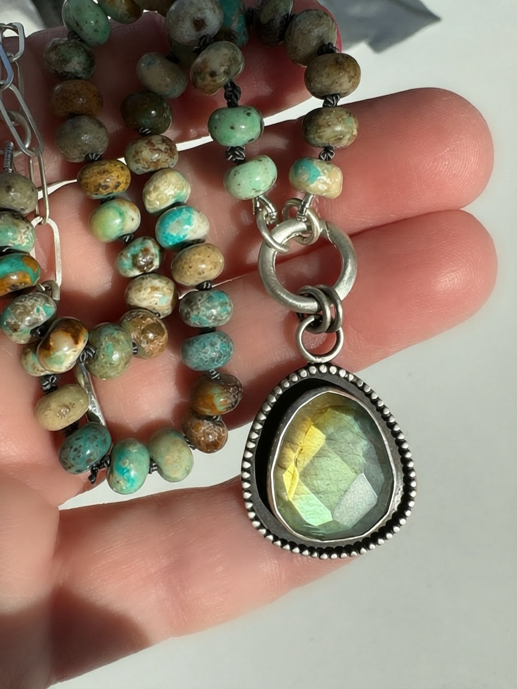 Close-up of the Desert Aurora rose-cut labradorite pendant showing its gold-to-green flash, fine silver bezel and oxidized satin finish.
