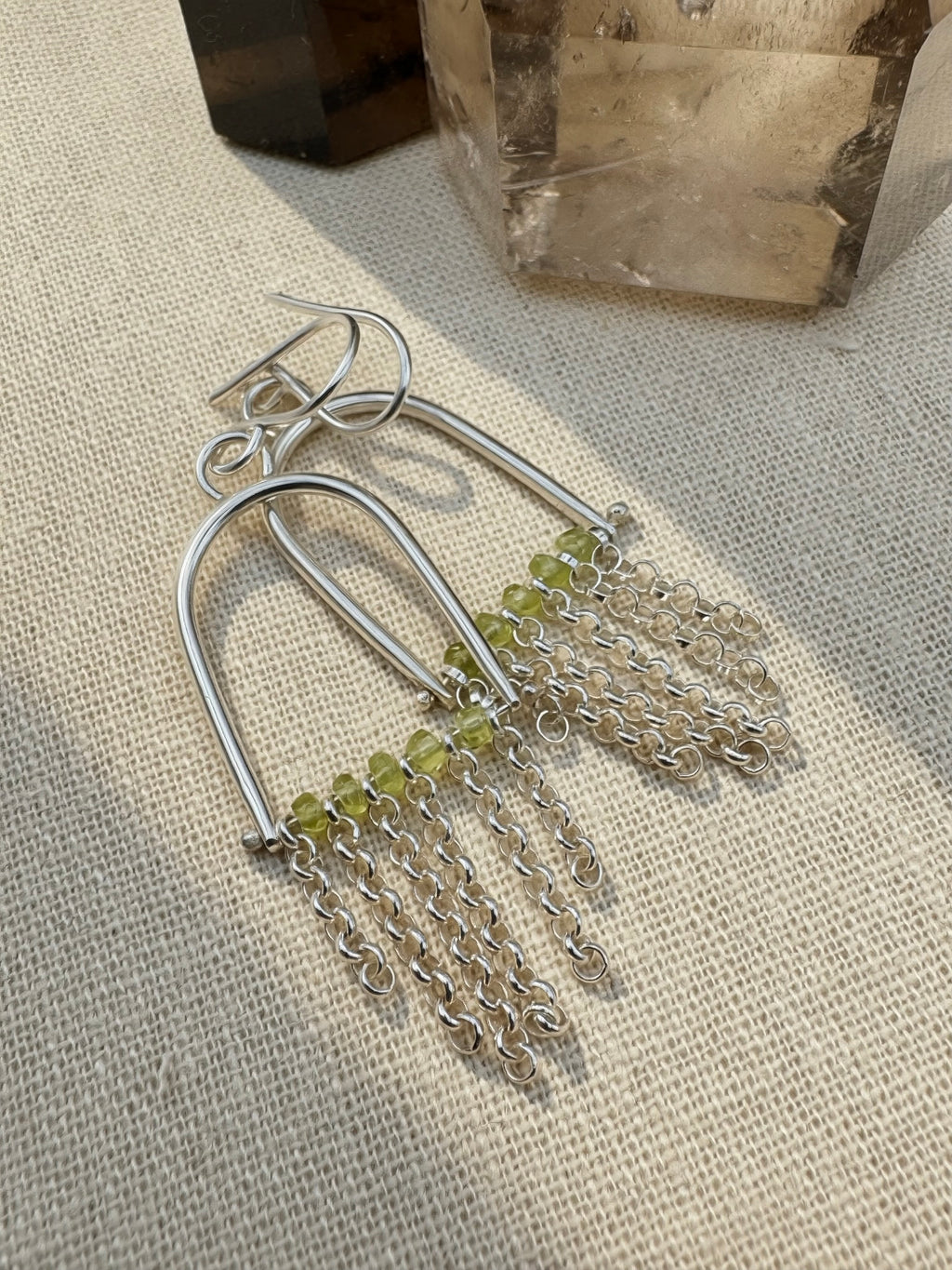 Close-up of natural Arizona Peridot beads with sterling silver chain fringe earring, volcanic gemstone detail
