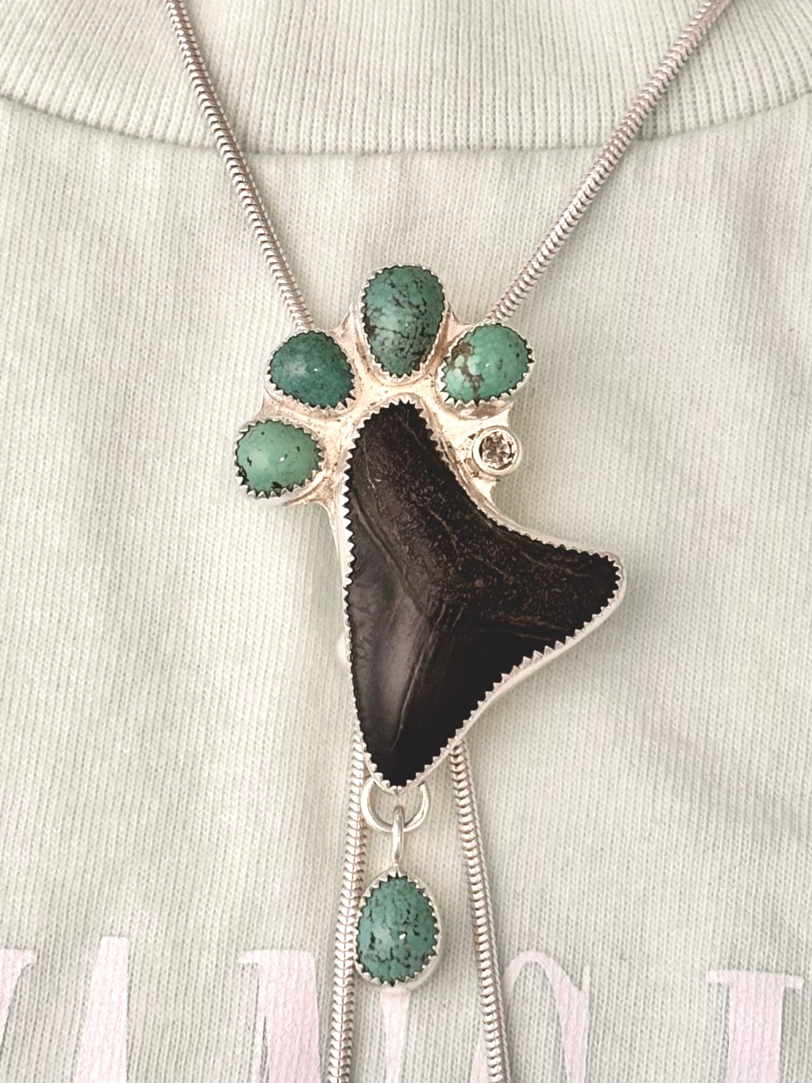 Sterling silver statement, Bolo Necklace with a megalodon fossil tooth, white sapphire and green turquoise on a t-shirt