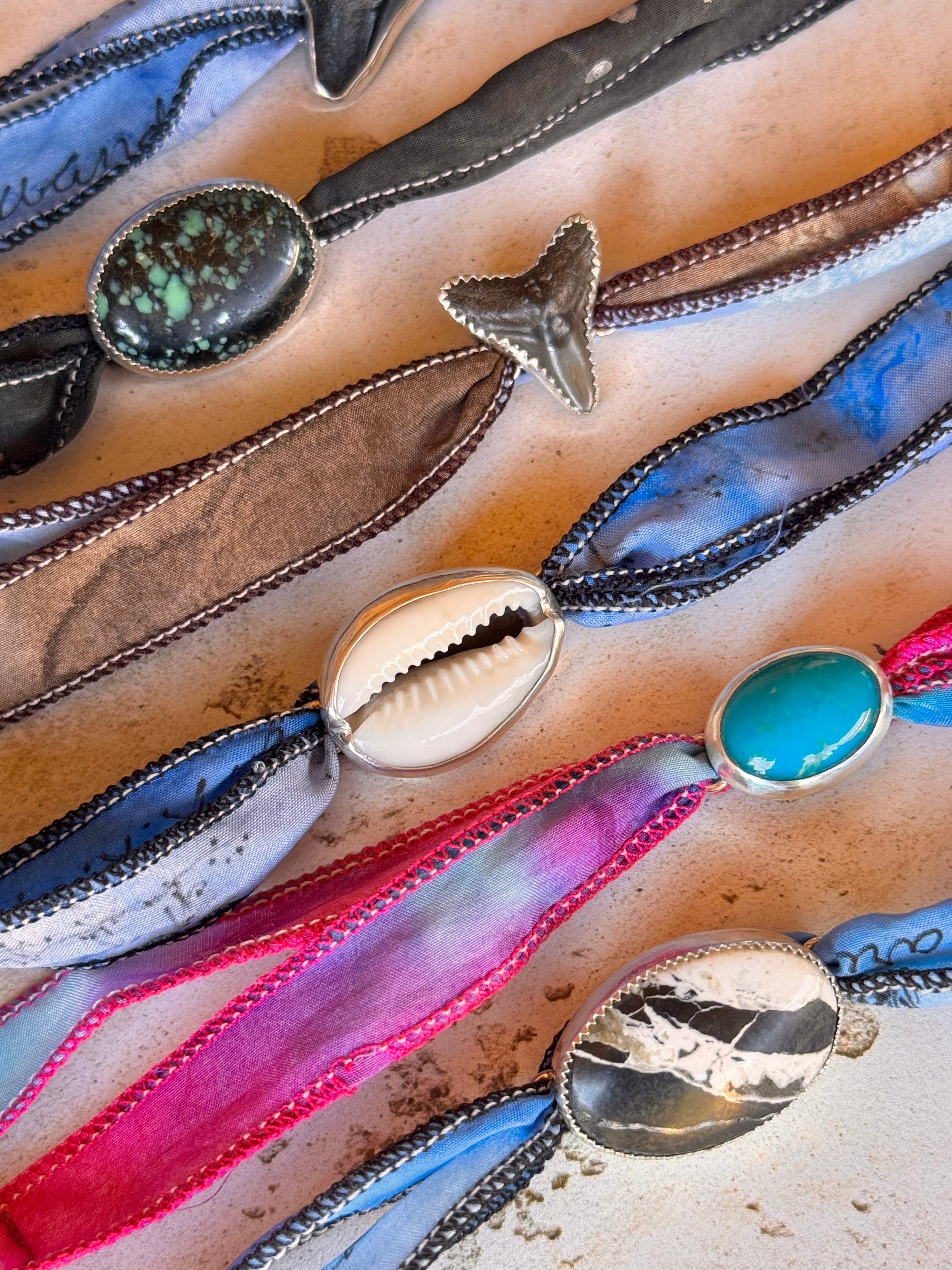 Close-up of colorful necklaces with various pendants on a textured surface