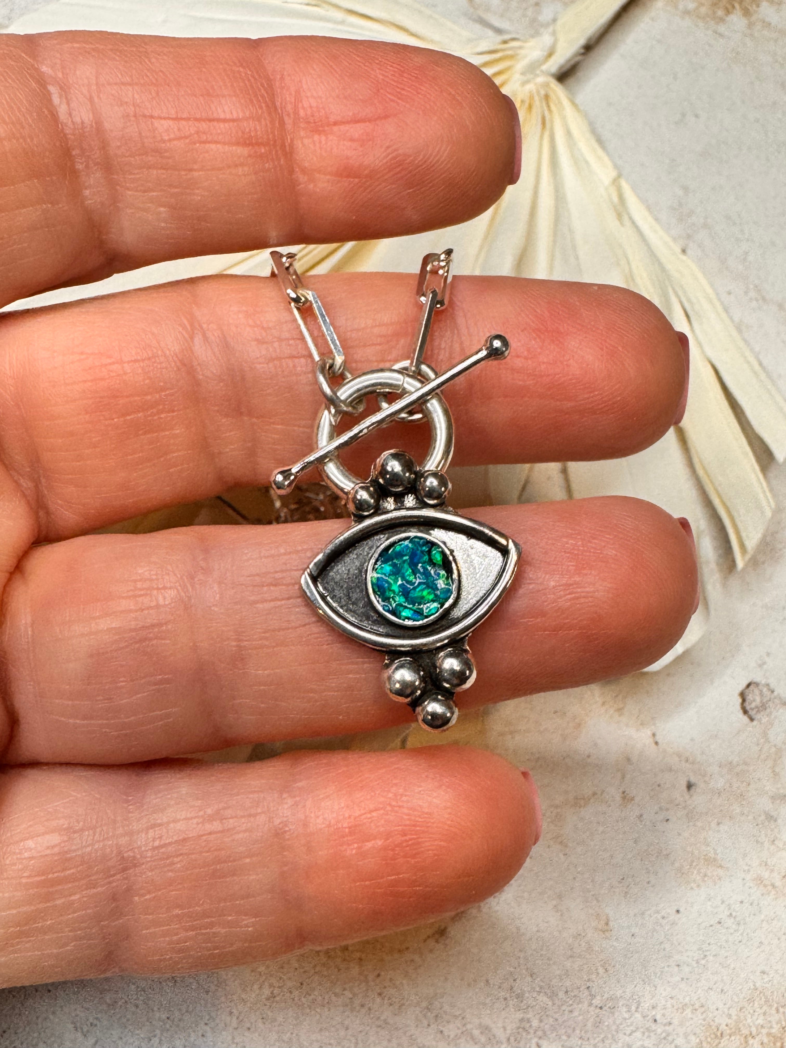 Silver necklace with green and blue opal inlay paperclip toggle chain against a neutral background