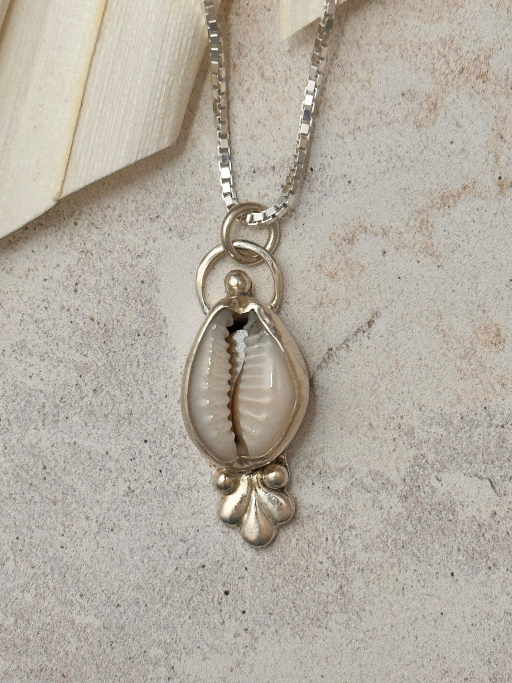 Silver necklace with a shell pendant on a textured surface