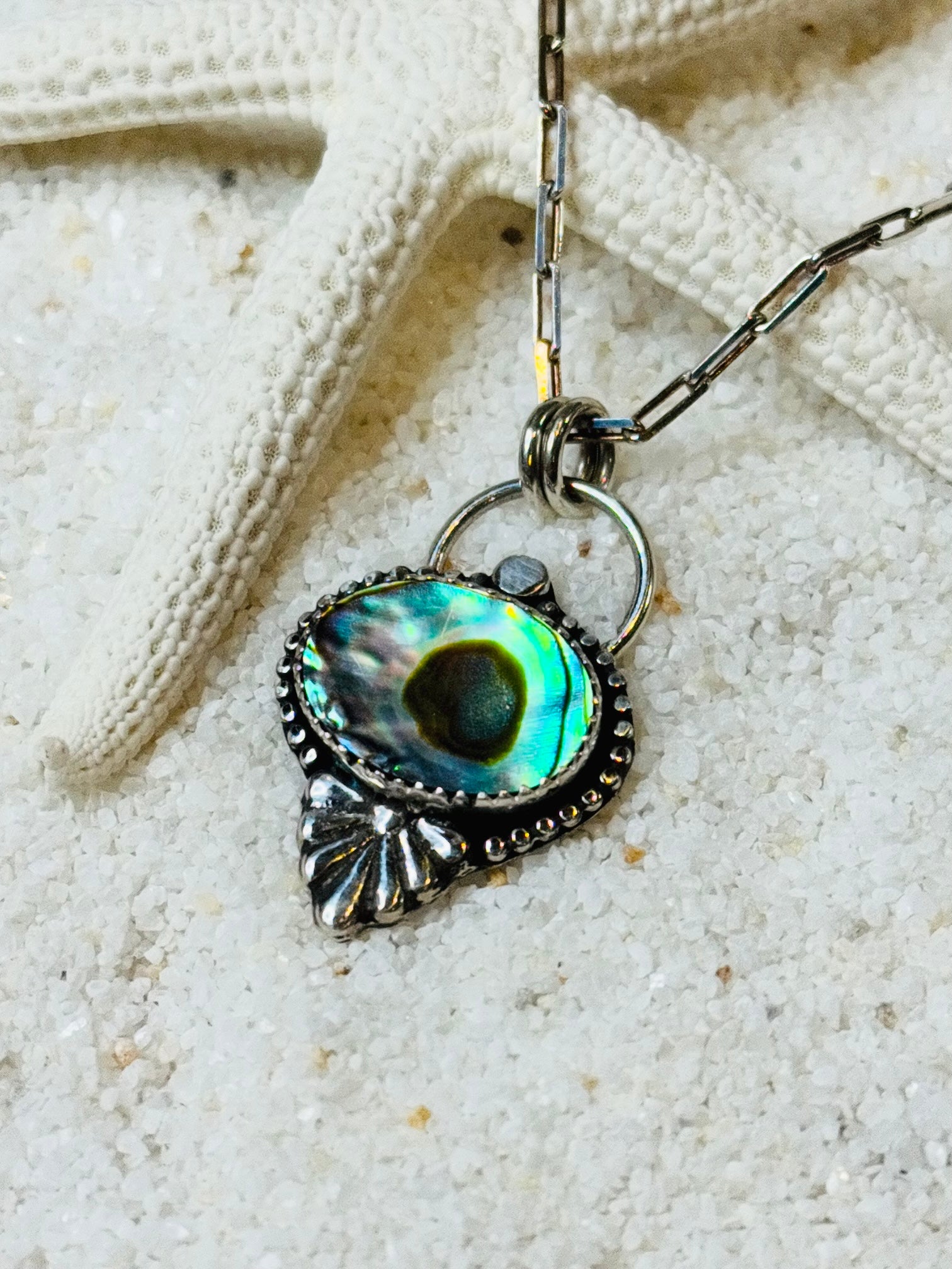Necklace with a shell pendant on a sandy background