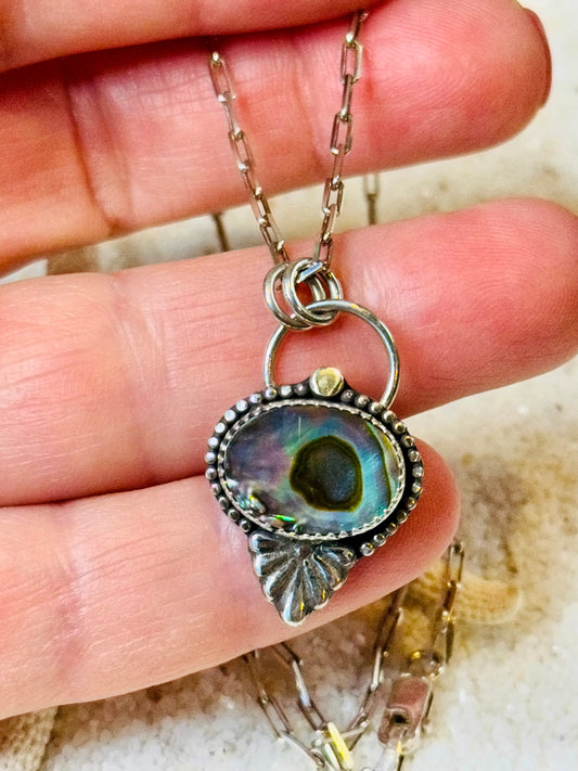 Abalone Necklace with a pendant held between fingers on a neutral background