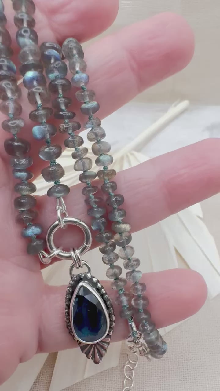 Blue Hour Bloom teal kyanite and labradorite necklace being held in hand