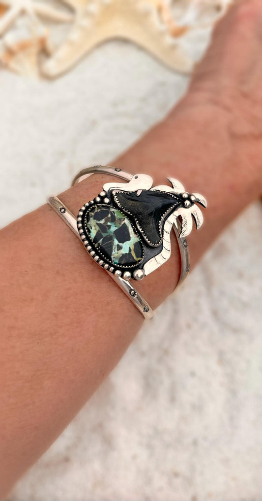 Silver bracelet with a turquoise stone, shark tooth, palm tree and an octopus.